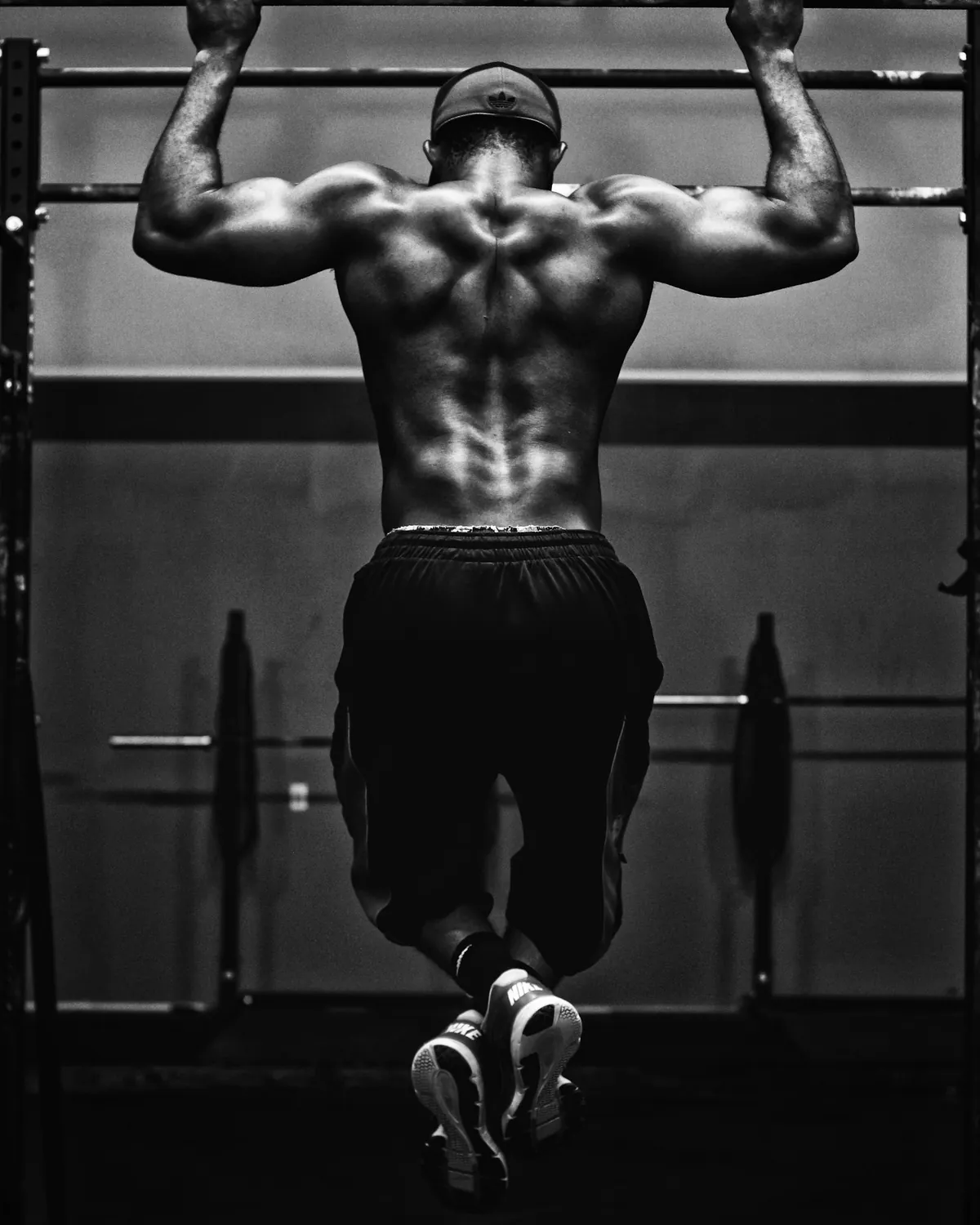 Espalda de un atleta haciendo dominadas en blanco y negro