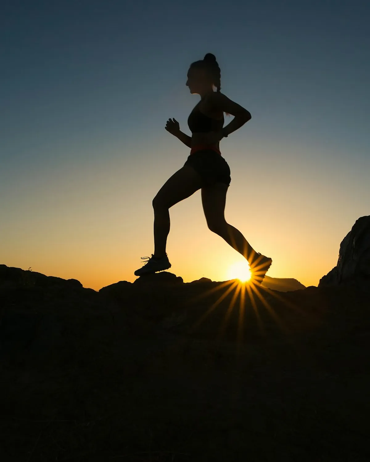 Silueta de una persona corriendo sobre roca al atardecer
